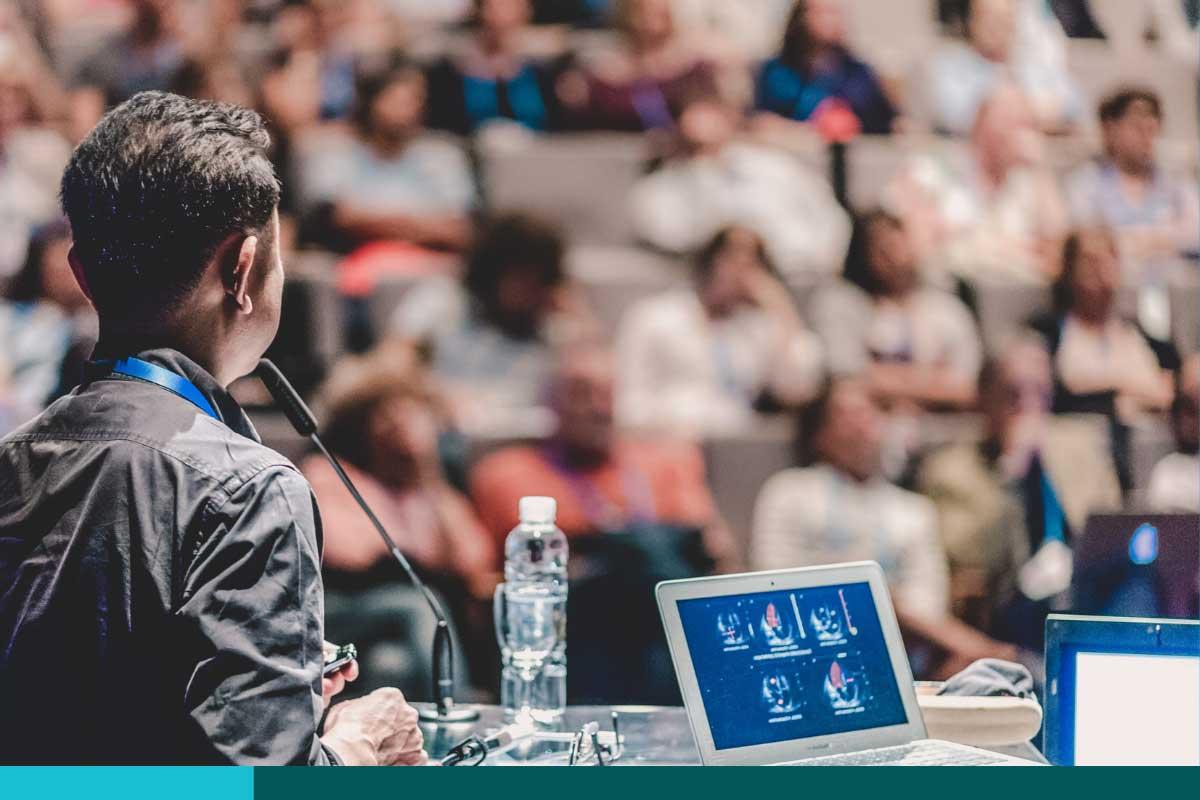 Looking out past a speaker in front of a conference audience