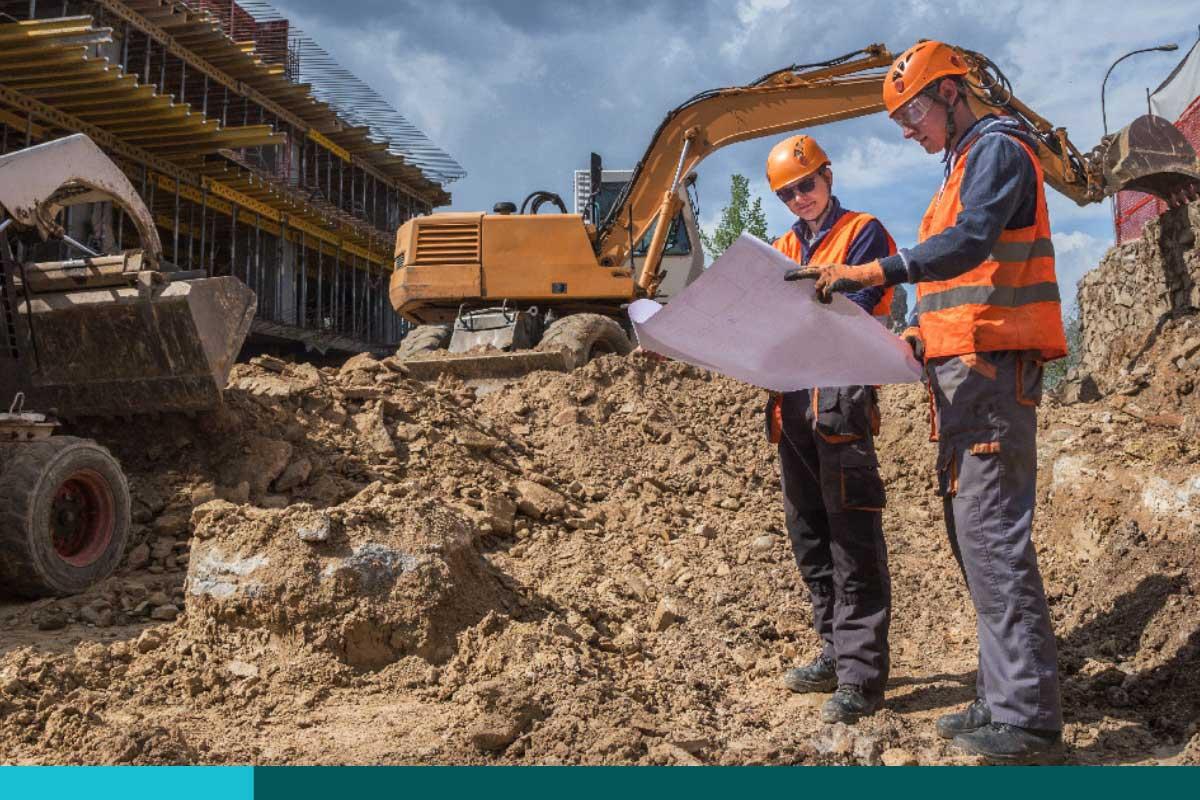 Two men wearing hard hats conferring at a job site